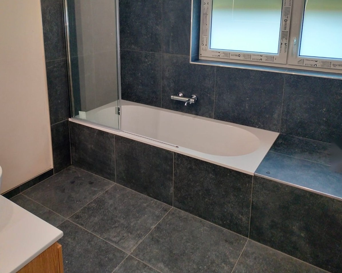 Inbouwbad met glazen badscherm, antracietkleurige tegels op vloer en wanden