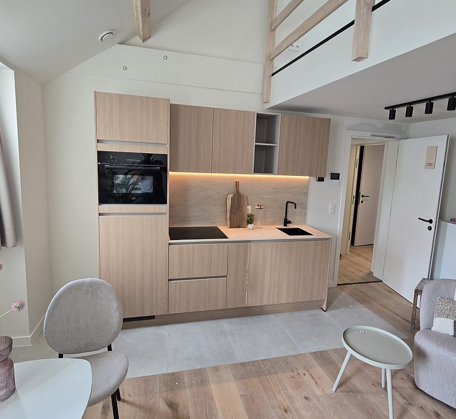 Open keuken in licht hout in een loft met houten vloer en zithoek