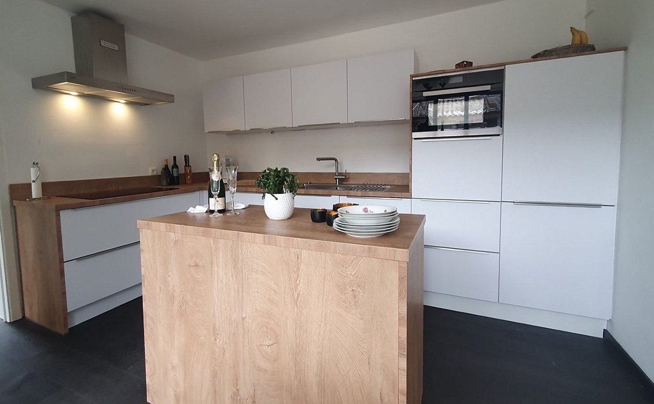 Witte keuken met eikenhouten eiland en dampkap in inox
