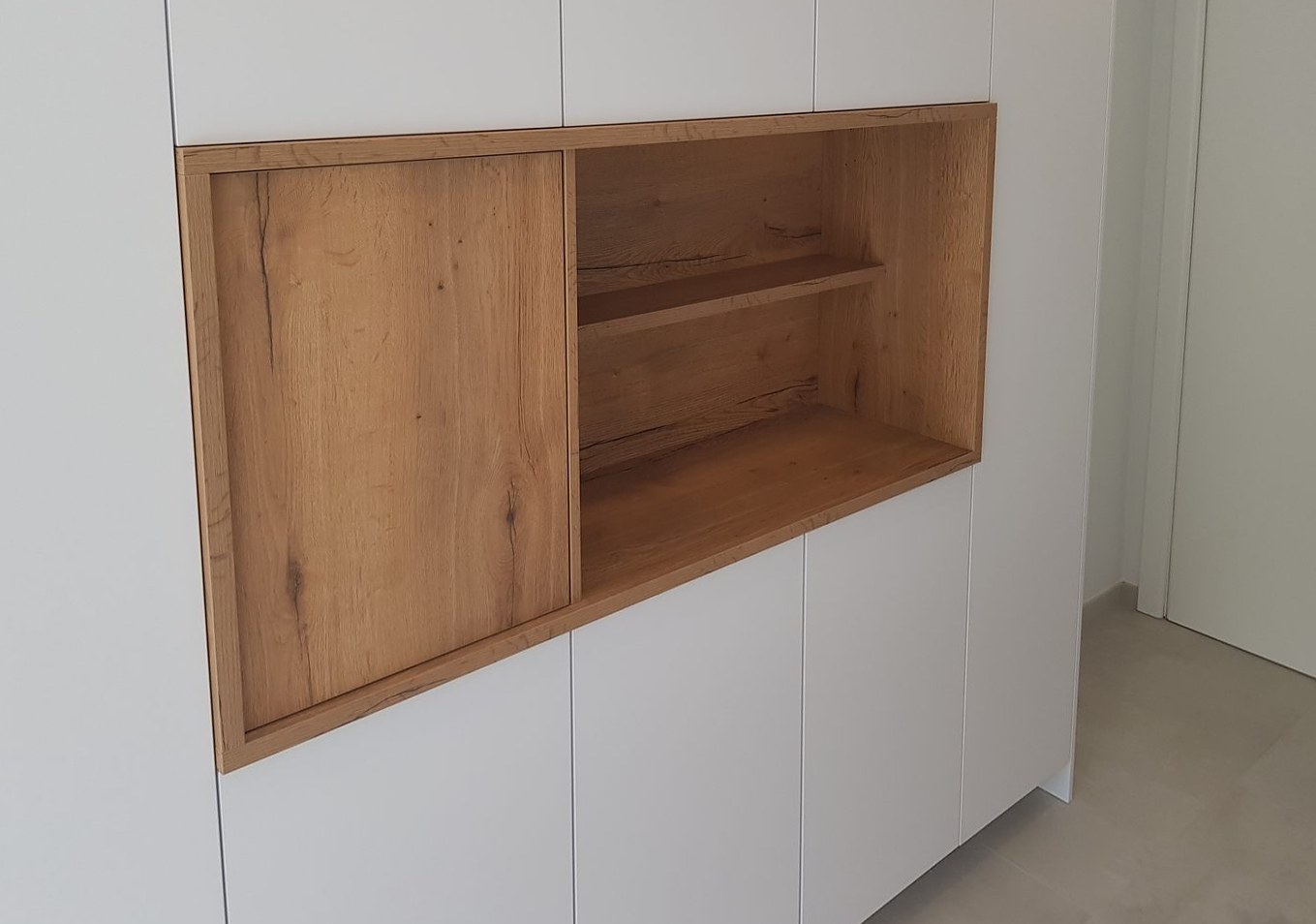 Open eikenhouten nis met schuifpaneel in een witte kastenwand