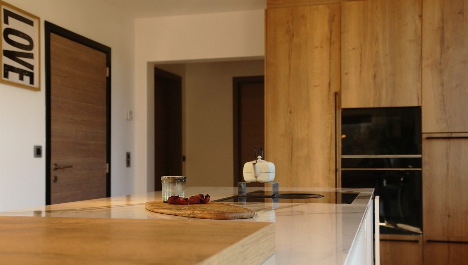 Îlot de cuisine avec plan de travail blanc aspect marbre et plan en bois surbaissé servant de bar