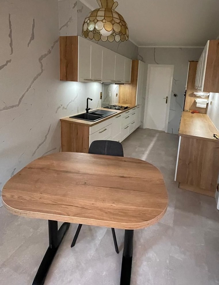Keuken met witte kasten en eik, marmerlook wanden en houten eettafel
