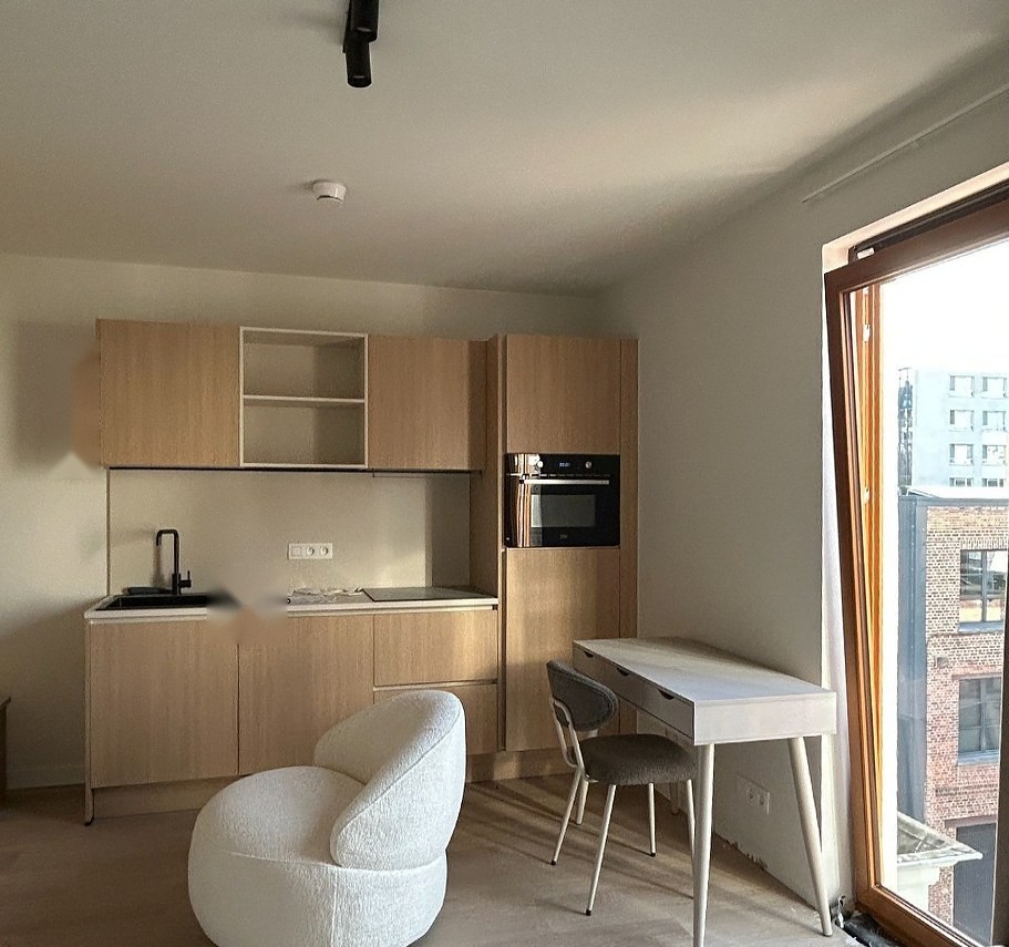Studiokeuken in licht hout met bureau en fauteuil bij het raam