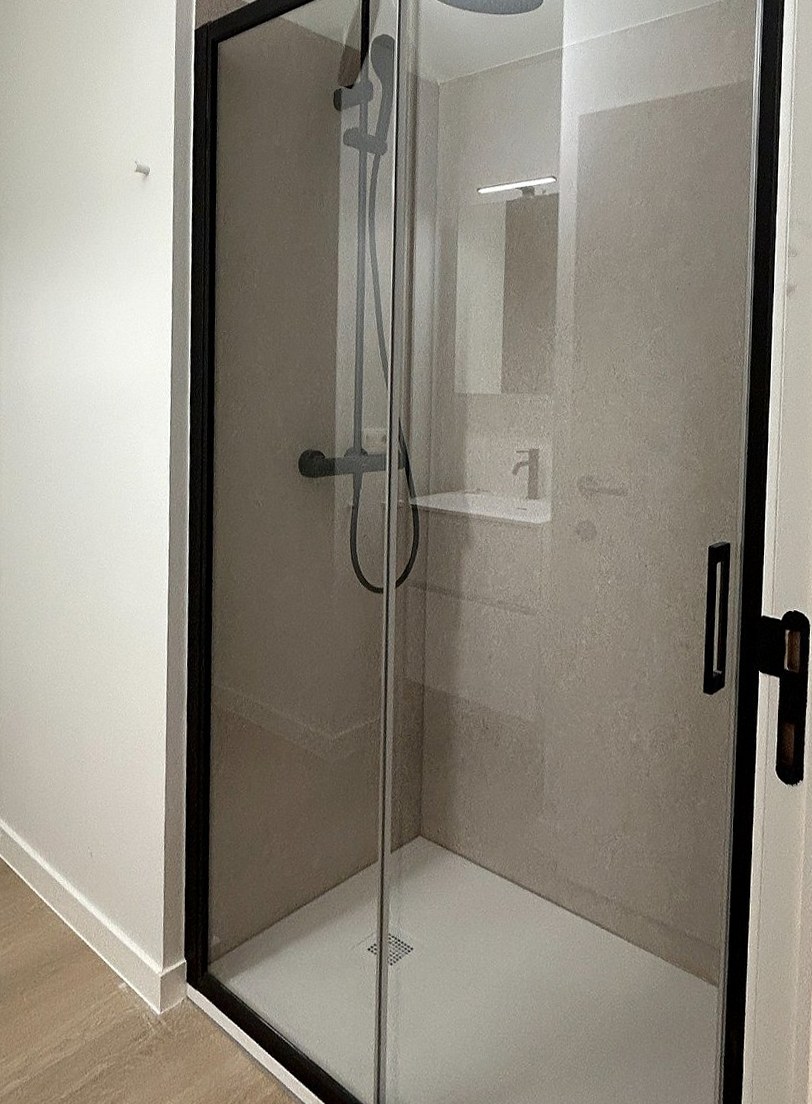 Douche met zwarte glazen schuifdeur en beige wanden