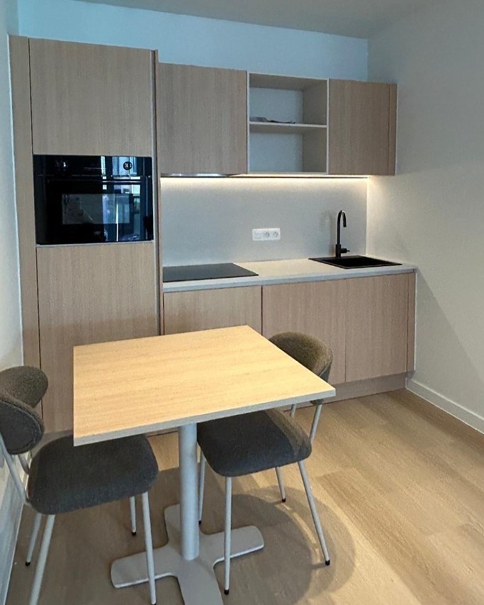 Kleine keuken in licht hout met open vakken en een eettafeltje voor twee
