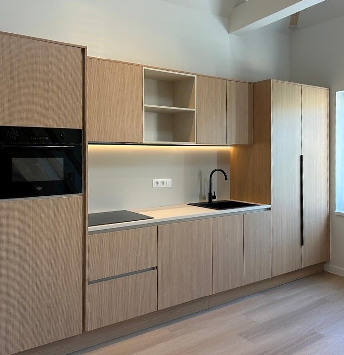 Keuken in licht hout met open bovenkast, verlichte achterwand en zwarte kraan